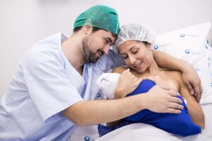 Benefícios da amamentação: a imagem ilustrativa mostra uma mulher segurando um recém-nascido em seus braços com um homem ao lado.