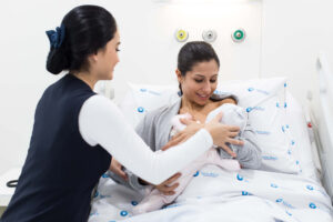 Benefícios da amamentação: a imagem ilustrativa mostra uma profissional da saúde auxiliando uma mãe a amamentar ainda no hospital.